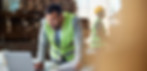 Warehouse worker in vest using latop.