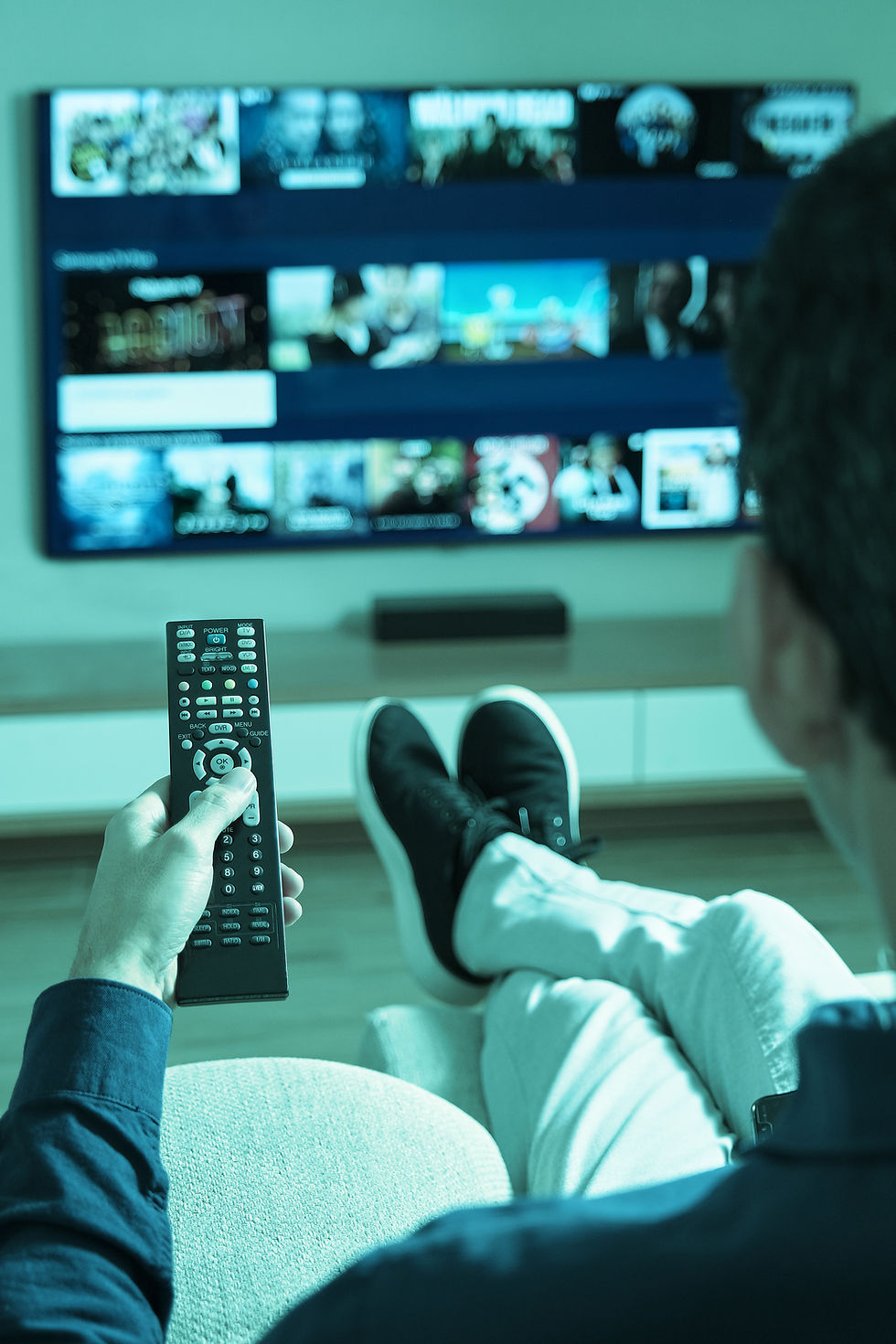 Person lounging and pointing remote at TV screen