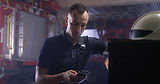 Firefighter in firehouse looking down at his phone with teal overlay.