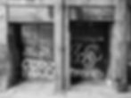 Black and white urban scene with graffiti on doorways and intricate glass panels in a glasgow alleyway by david gulliver photography