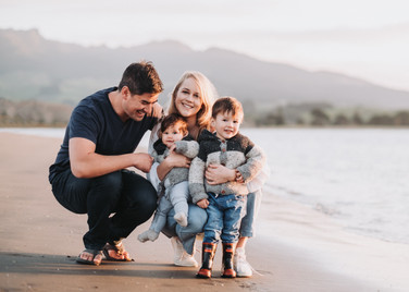 Family photo on Raglan beach in New Zealand in front of a mountain by the sea