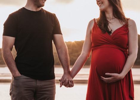 Pregnant couple holding hands at sunset in Raglan at the beach on a maternity photoshoot