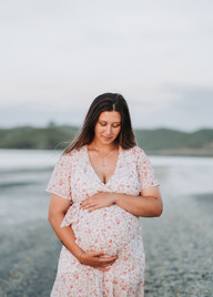 Pregnant woman having photographs taken on the beach in Raglan