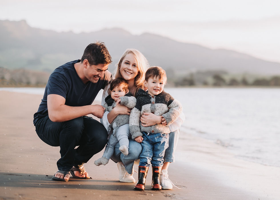 Family photo on Raglan beach in New Zealand in front of a mountain by the sea