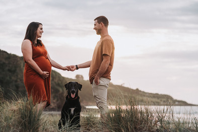 Pregnant couple with dog at Raglan beach during maternity photos