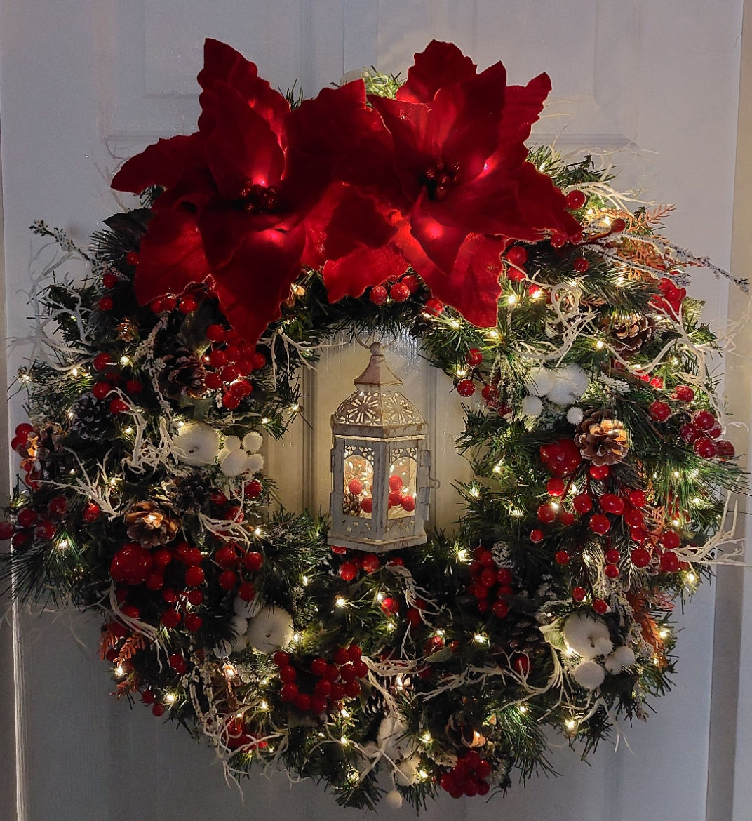 Large 22 inch Evergreen Wreath. Vibrant red poinsettias, berries & white accents. Battery timer lights that finish in a centr