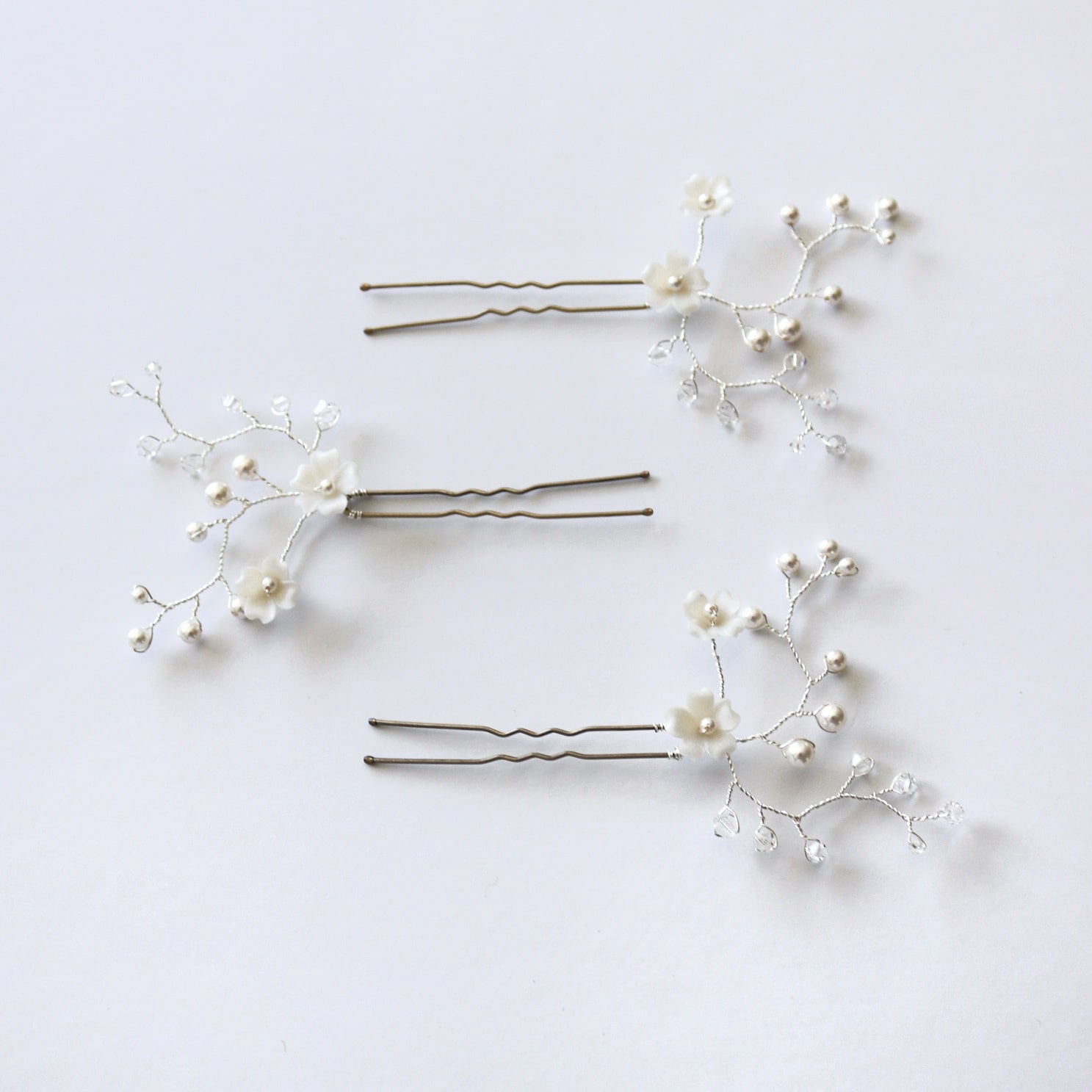 Set of three bridal hair pins embellished with sprigs of ivory pearls, clear crystals and ivory clay flowers