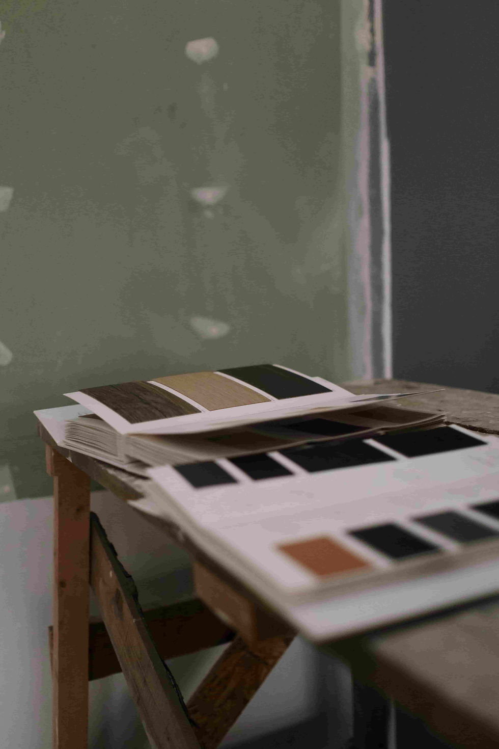 Mesa con muestras de colores y, al fondo, una pared pintada de verde.