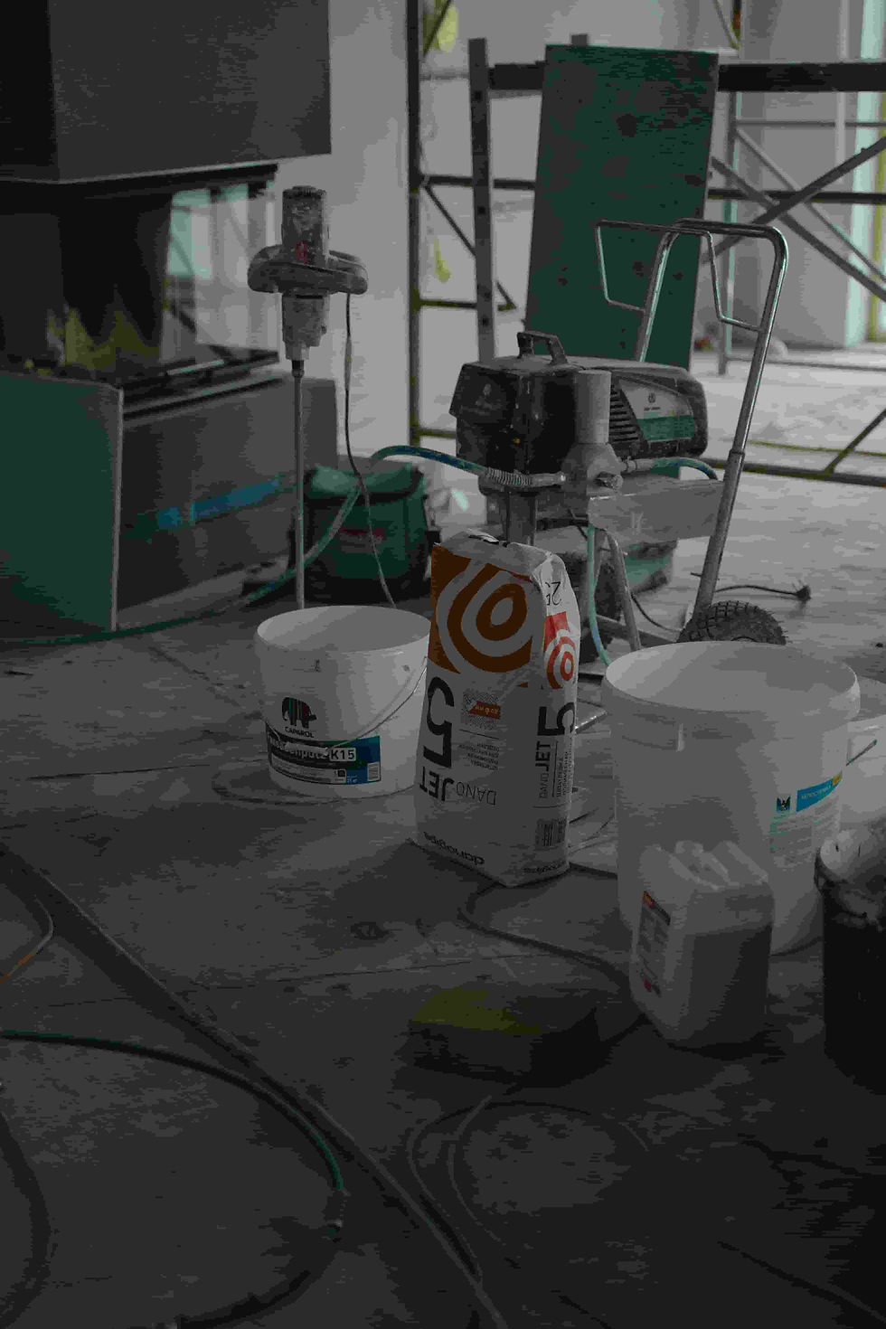 Pinturas y herramientas de pintura en el suelo durante una reforma, junto con utensilios de trabajo adicionales.