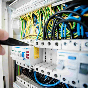 Elektrikár kontroluje a nastavuje ističe v elektrickom rozvádzači s množstvom farebných káblov