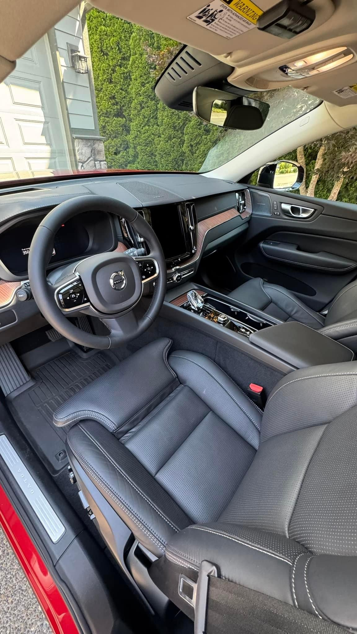 “Interior of a modern red Volvo vehicle featuring black leather seats, a digital dashboard, multifunction steering wheel, and a clean center console with chrome accents.”