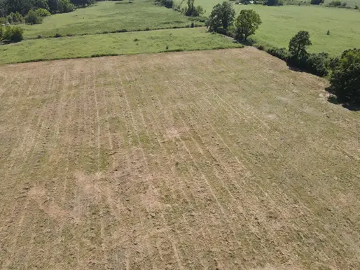 Aerial view of a cleared rural field bordered by green pasture and trees near Joplin Missouri