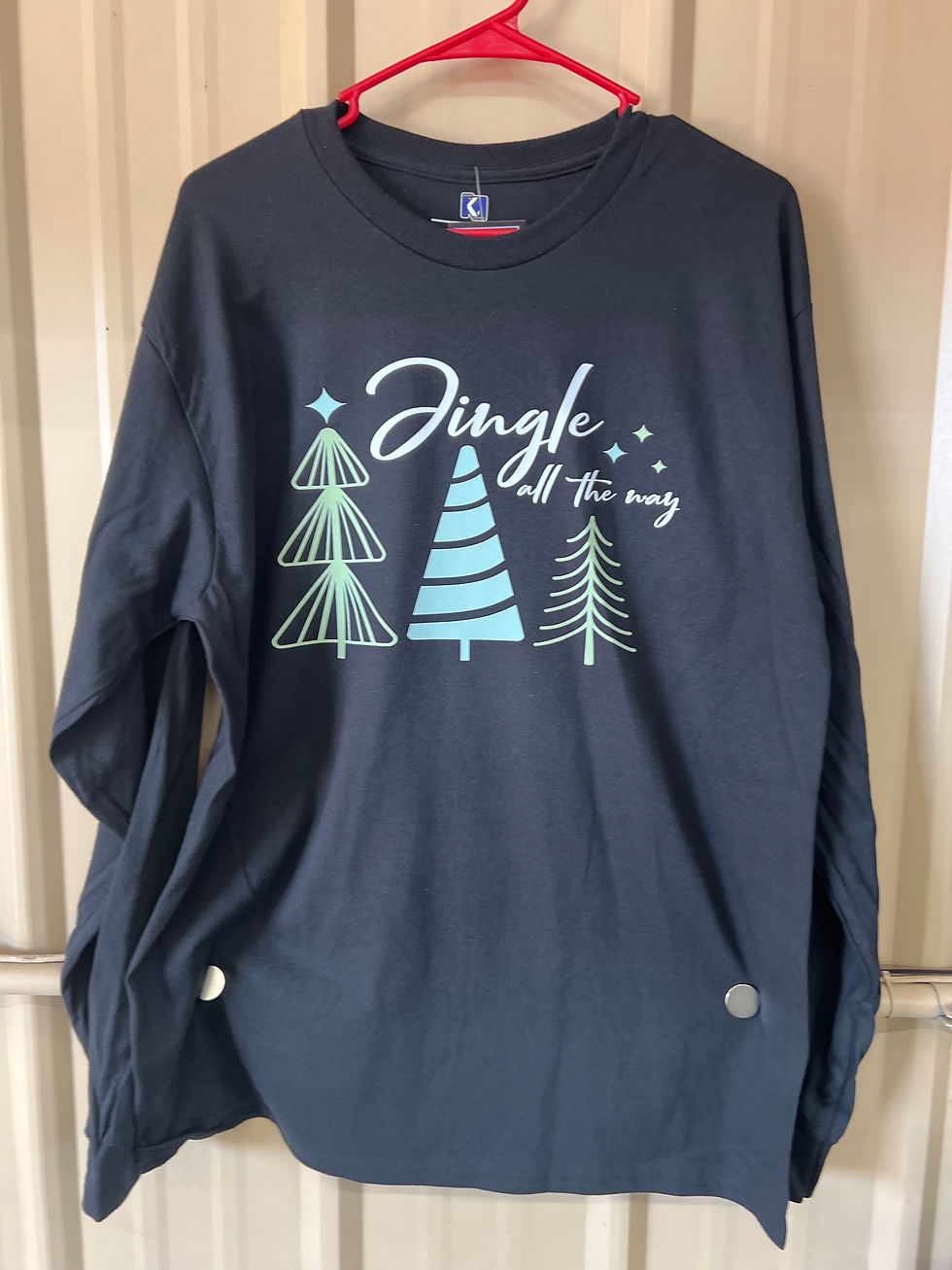 Front view of the "Jingle All The Way" long-sleeve shirt in black, featuring minimalist green tree designs and festive script