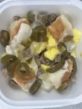 Image of a food bowl, the food consists of eggs, sausage, biscuits, cheese
