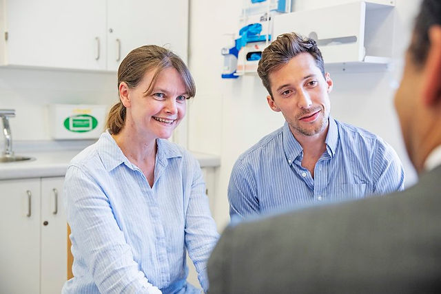 Photo of a couple discussing their fertility options at a BCRM consultation. Photo is taken of the couple over the shoulder of the consultant.