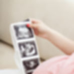 Pregnant woman holding a printout of baby scans, representing public relations for the IVF and fertility sector