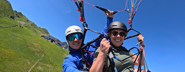 Gleitschirmflug über grüne Berge