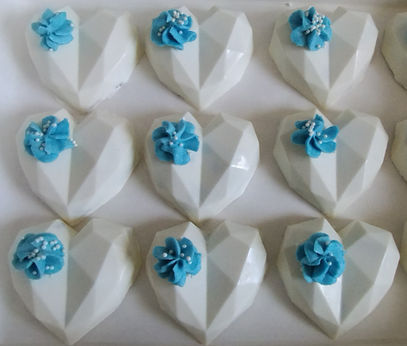White geometric heart treats topped with blue frosting and sprinkles.