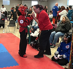 Adult female instructor coaching a boy student in competitive sparring