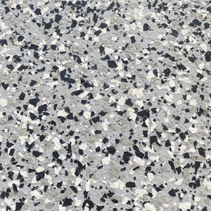 Close-up of a decorative epoxy flake garage floor showcasing a gray, white, and black flake blend with a textured, durable finish.