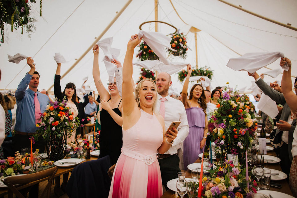 Wedding guests in Pole Marquee swinging napkins in delight.