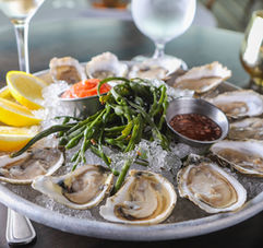 A dozen oysters on the half shell with lemon wedges