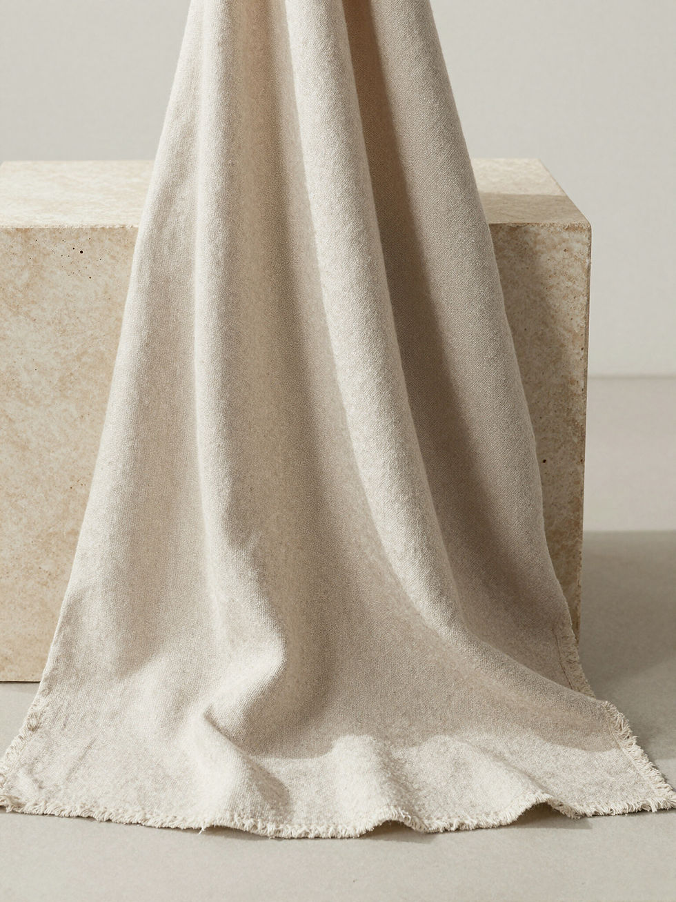 Draped beige textured linen fabric over a stone block