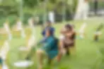 A candid shot of wedding guests sitting in the rain, wet but smiling, as they watch Alicia and Arklon’s ceremony at Caymanas Golf Club