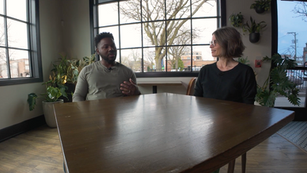 A man and woman sit at a table talking