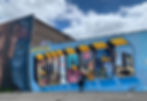 woman standing in front of mural