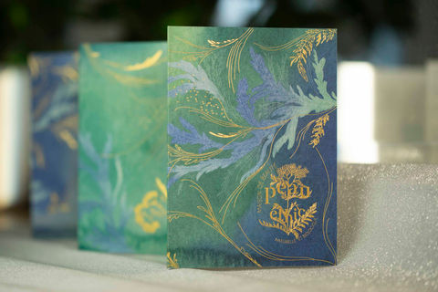 dépliant bleu, vert et or avec illustrations végétales de tiges souples et de feuilles