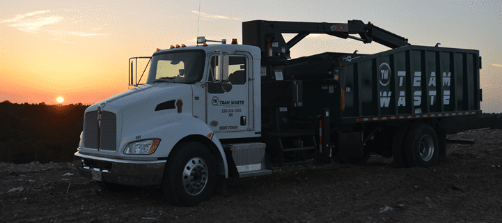 Truck driving down street with sun setting in background