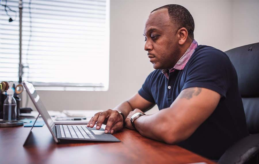 Side profile of man using laptop for Univerus Waste & Recycling software