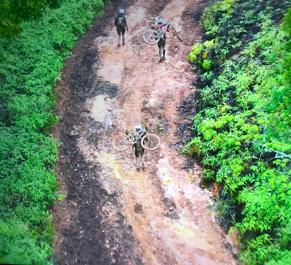 Racers carrying bikes up muddy hill