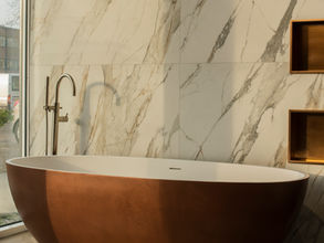 Badkamer met bronzen bad, marmerlook muur en nisjes met brons
