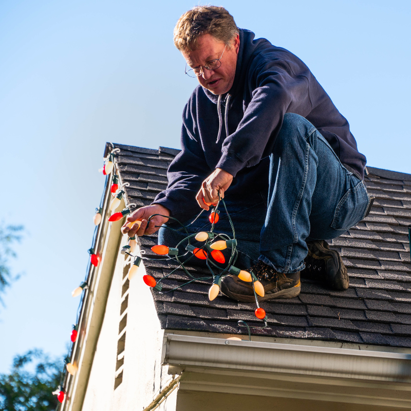 Picutre of a man installing his own christmas lights.
