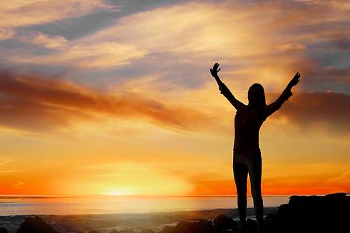 Woman holding arms in air by the beach