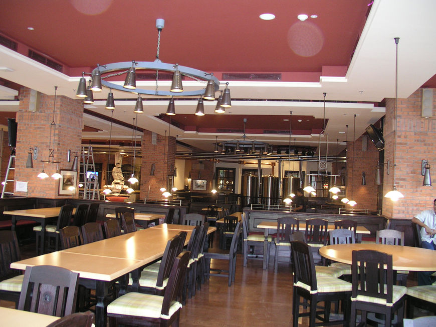 Architectural interior of a rustic alpine restaurant showcasing wood-paneled walls, traditional wooden dining sets, and structured wood ceilings.
