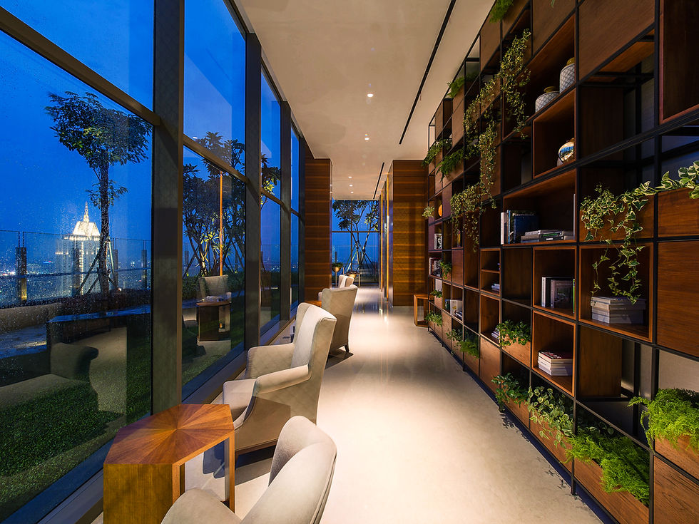 Modern high-rise lounge corridor featuring large floor-to-ceiling windows with a nighttime city view, comfortable armchairs, and a large wooden grid bookshelf filled with plants.