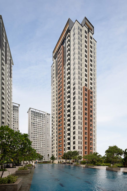 Main entrance gate of the Serpong M-Town apartment complex featuring modern architecture, security pillars, and green surroundings.