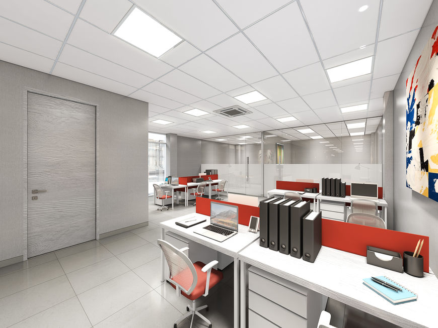 Open-plan office workspace with white desks, red privacy dividers, black chairs, file organizers, and abstract wall art.