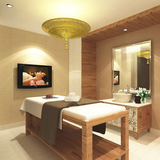 Relaxing spa treatment room featuring a wooden massage table, warm ambient lighting, an ornate gold ceiling lamp, and a modern vanity sink.