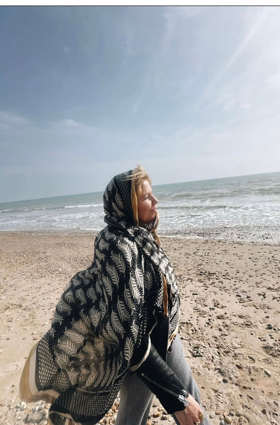 Woman in scarf on sunny beach, a moment of stress reduction