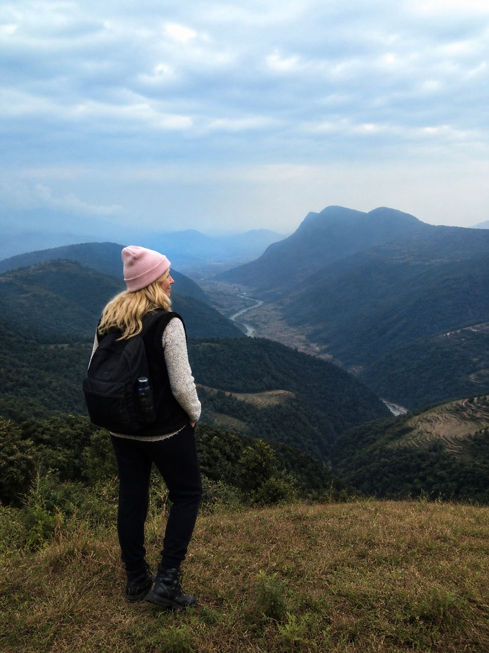Woman overlooking mountain valley, finding stress reduction