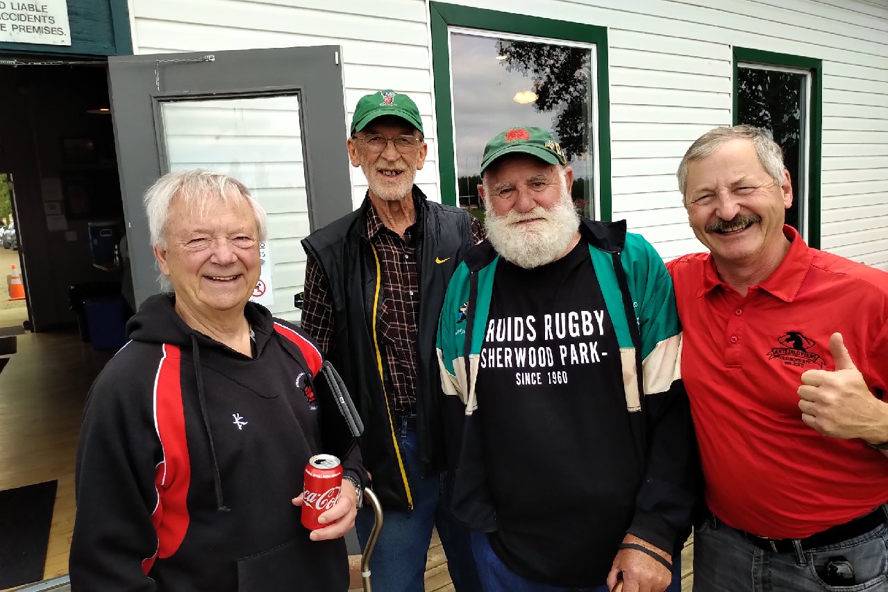 Lynn Davies at Lynn Davies Rugby Park with fellow longtime club members, wearing a 'Druids Rugby Sherwood Park — Since 1960' shirt