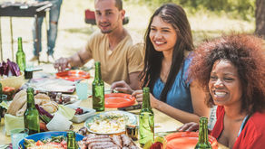 A group of friends eating together outdoors while one person grills food. Everyone is smiling and engaged, enjoying the shared meal and connection. The scene represents gratitude, togetherness, and the positive impact of expressing thanks in daily life.