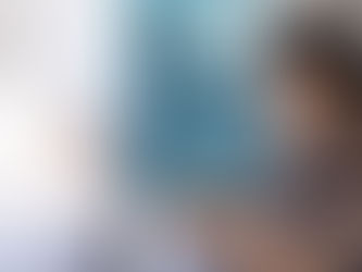 A Hispanic lady sitting quietly in soft morning light, writing in a journal on her tablet, symbolizing self-reflection and self-forgiveness after divorce.