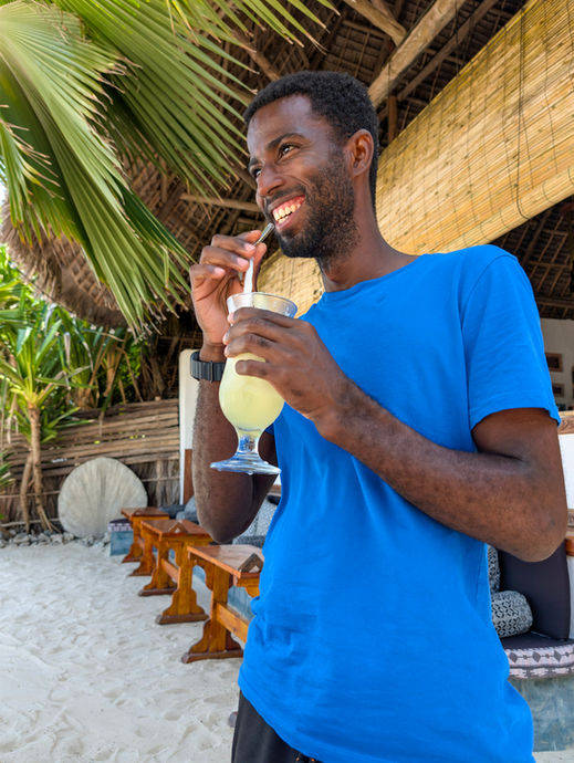 Guest smiling while enjoying a juice and looking at the ocean at Boutique Hotel Matlai Zanzibar.