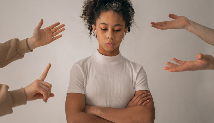 A young lady looking down as she is confronted by assumed relatives. We see only hands on her left and right.