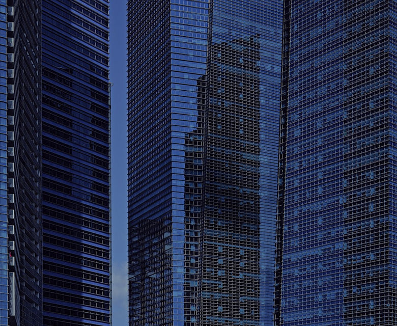 Modern glass skyscrapers reflecting blue sky and clouds.